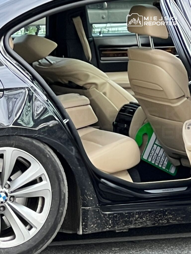 Wnętrze samochodu luksusowej marki z beżowym tapicerowaniem oraz odchyloną tylną kanapą.