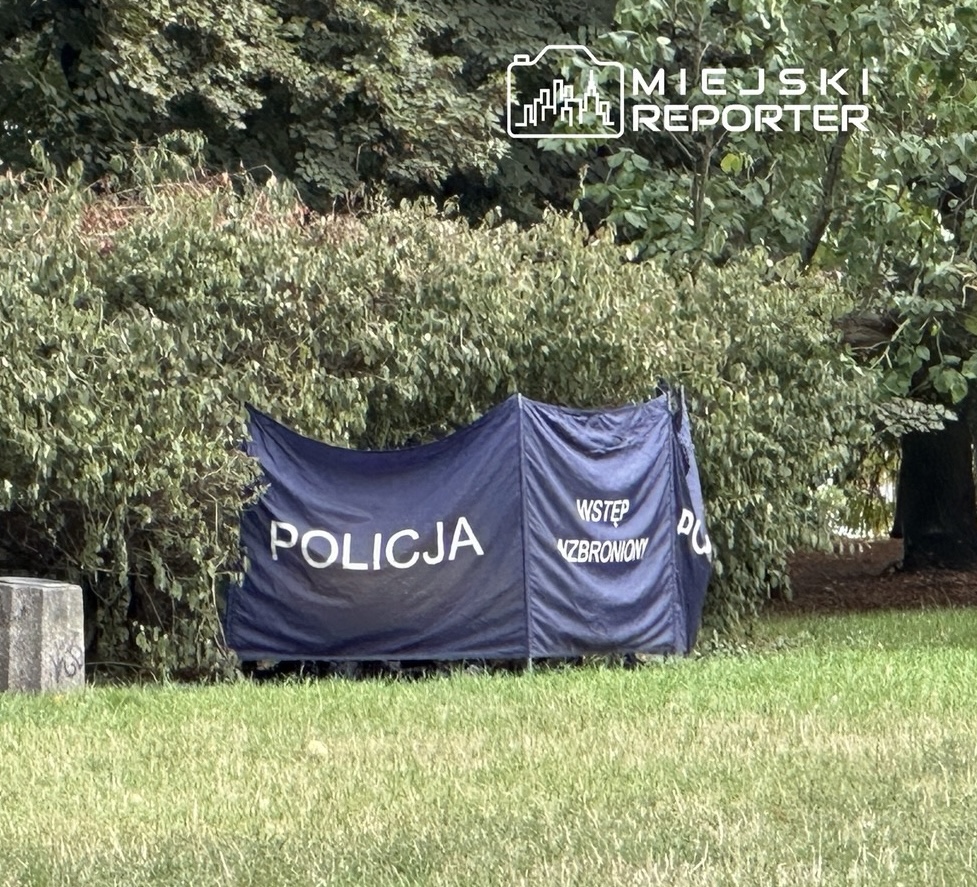 Namiot policyjny z napisem "POLICJA" i "WSTĘP WZBRONIONY" ustawiony w zielonym otoczeniu.