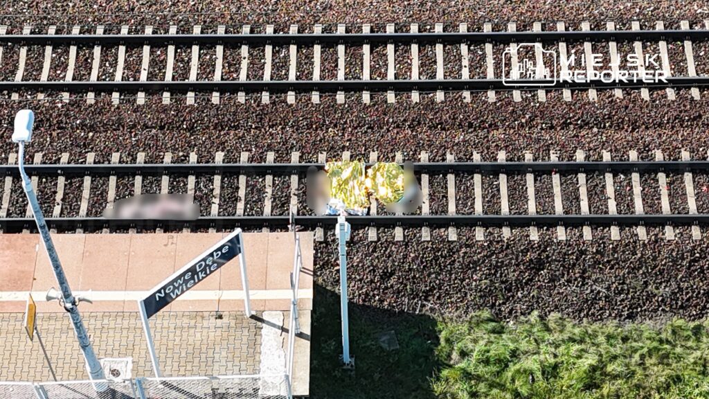 Na stacji kolejowej Nowe Dębe widoczny jest tor kolejowy oraz znak stacyjny, obok leżą metalowe przedmioty.