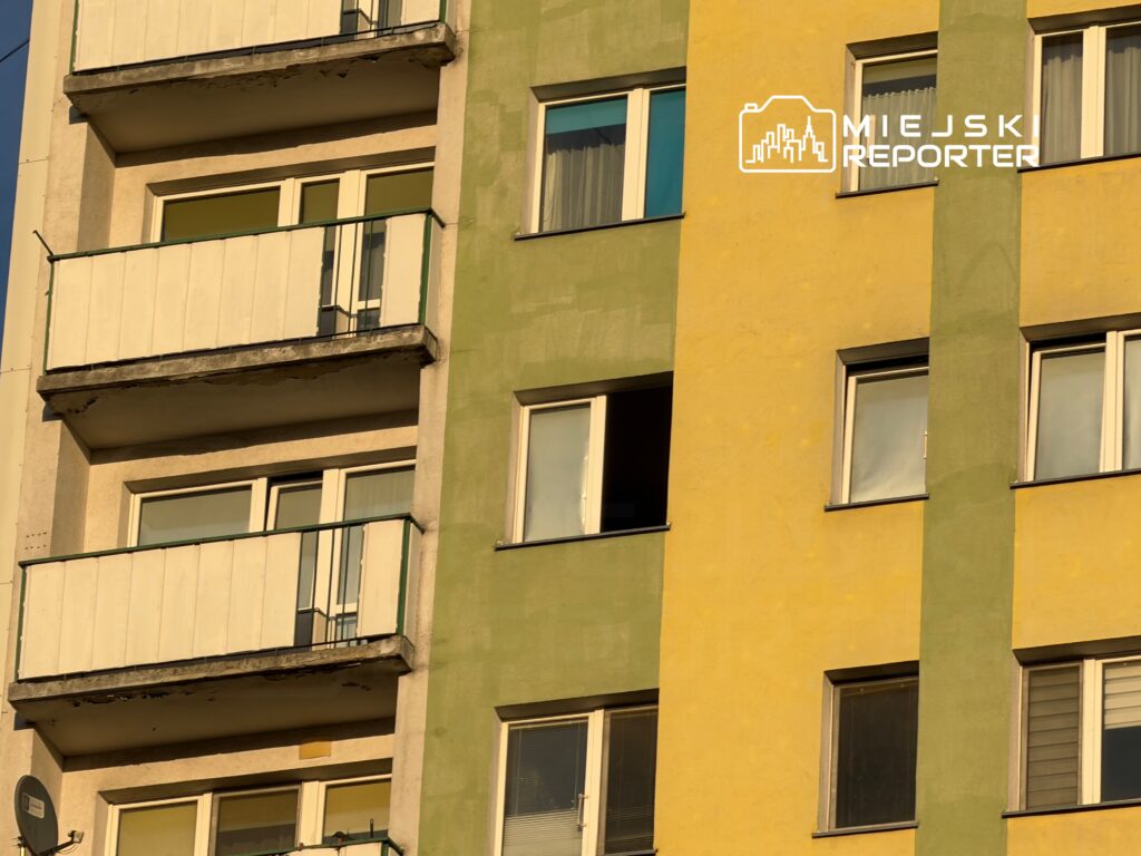 Balkony w bloku mieszkalnym z żółtą i zieloną elewacją, z widocznymi oknami i zewnętrznymi balustradami.