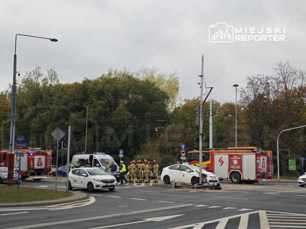 Na skrzyżowaniu stoją strażacy oraz karetka, obok uszkodzony samochód osobowy i woz strażacki.