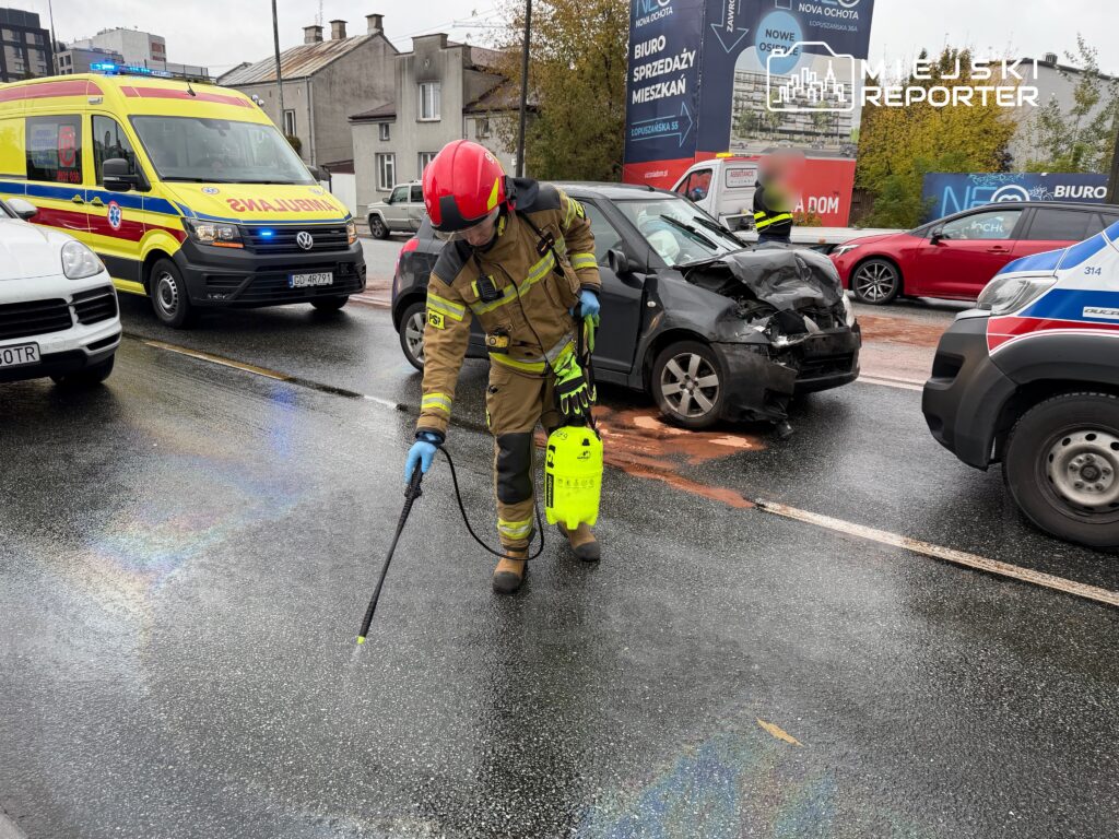 Strażak w mundurze używa urządzenia do czyszczenia drogi po wypadku samochodowym na miejskiej ulicy.