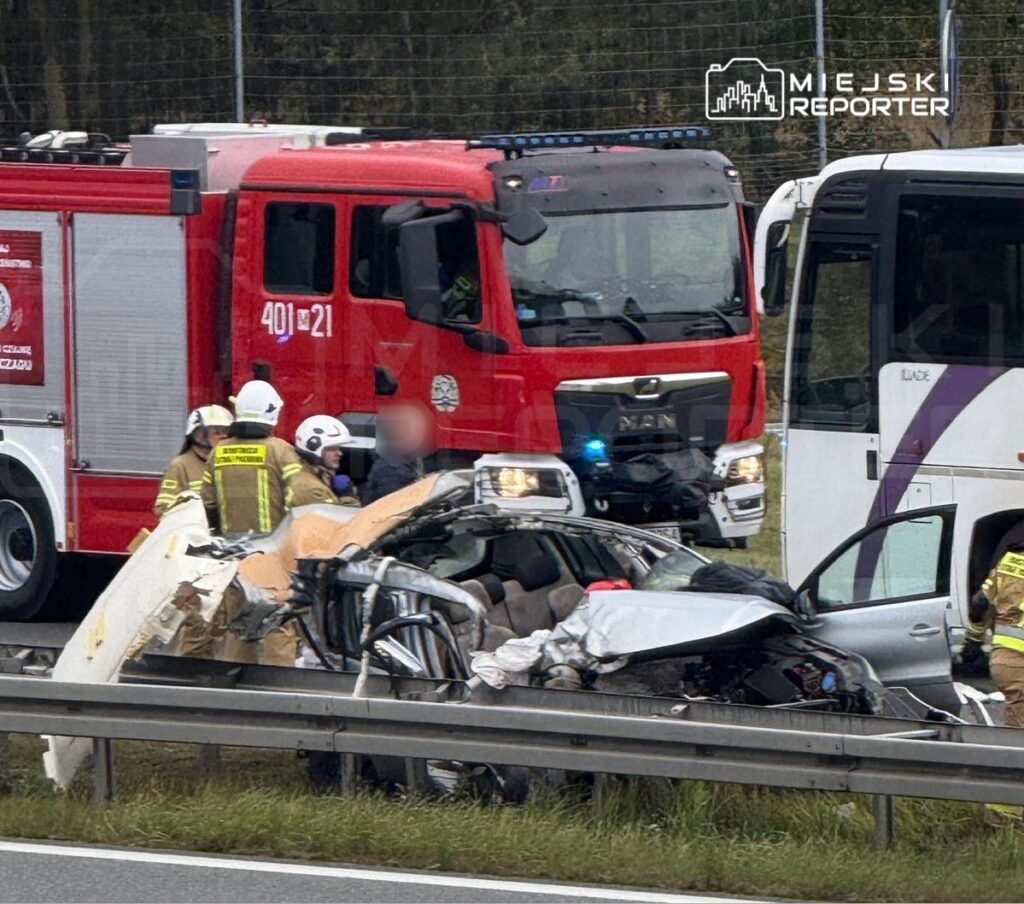 Ratownicy medyczni udzielają pomocy poszkodowanemu w wypadku drogowym obok rozbitego samochodu na autostradzie.
