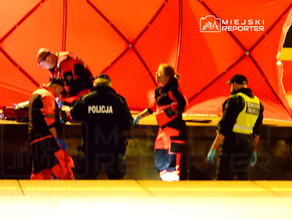 Czterech ratowników medycznych i policjantów pracuje przy rozłożonym namiocie ratunkowym.
