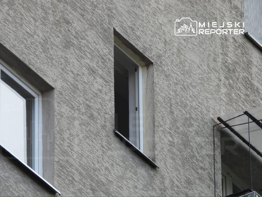 Dwa okna w elewacji budynku z tynkiem o strukturze przypominającej zarys.