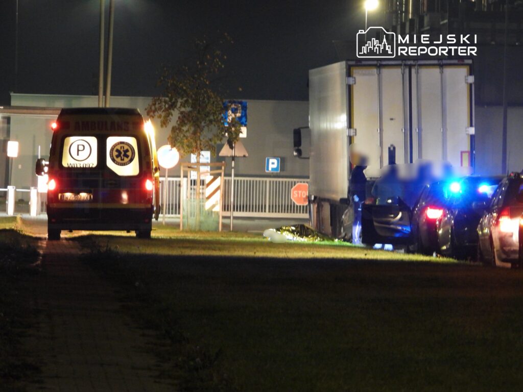 Ambulans zaparkowany w nocy obok ciężarówki, a policja prowadzi czynności na miejscu zdarzenia.