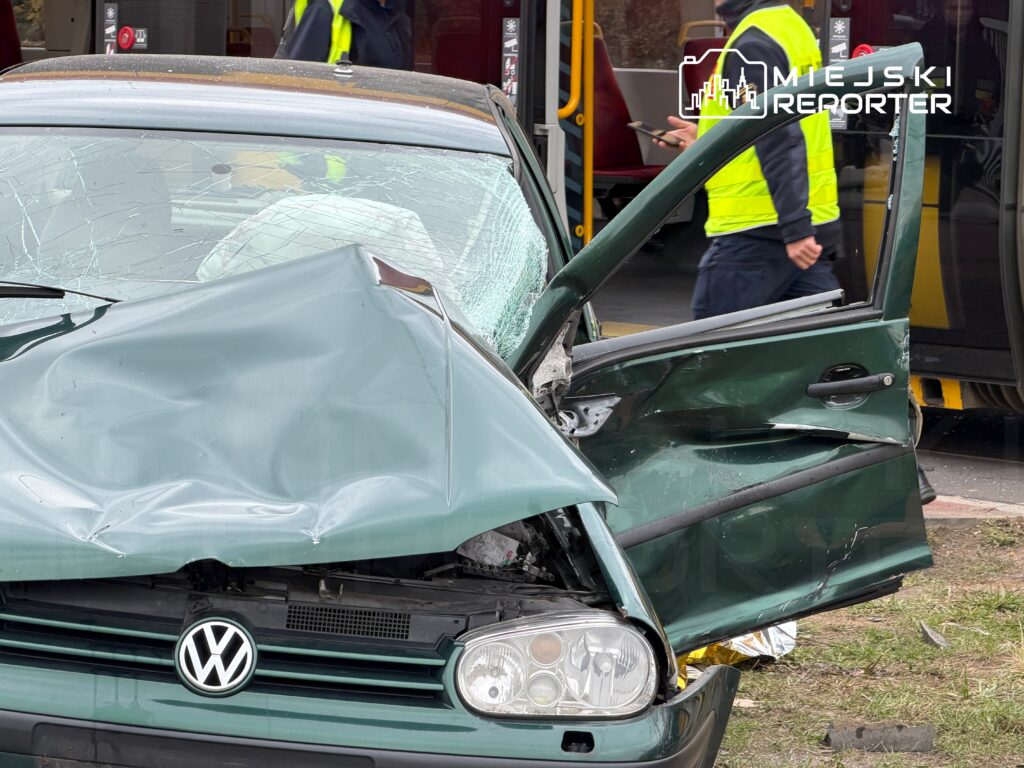 Zniszczony samochód osobowy marki Volkswagen z wgniecioną maską i uszkodzoną szybą stoi obok przystanku autobusowego.