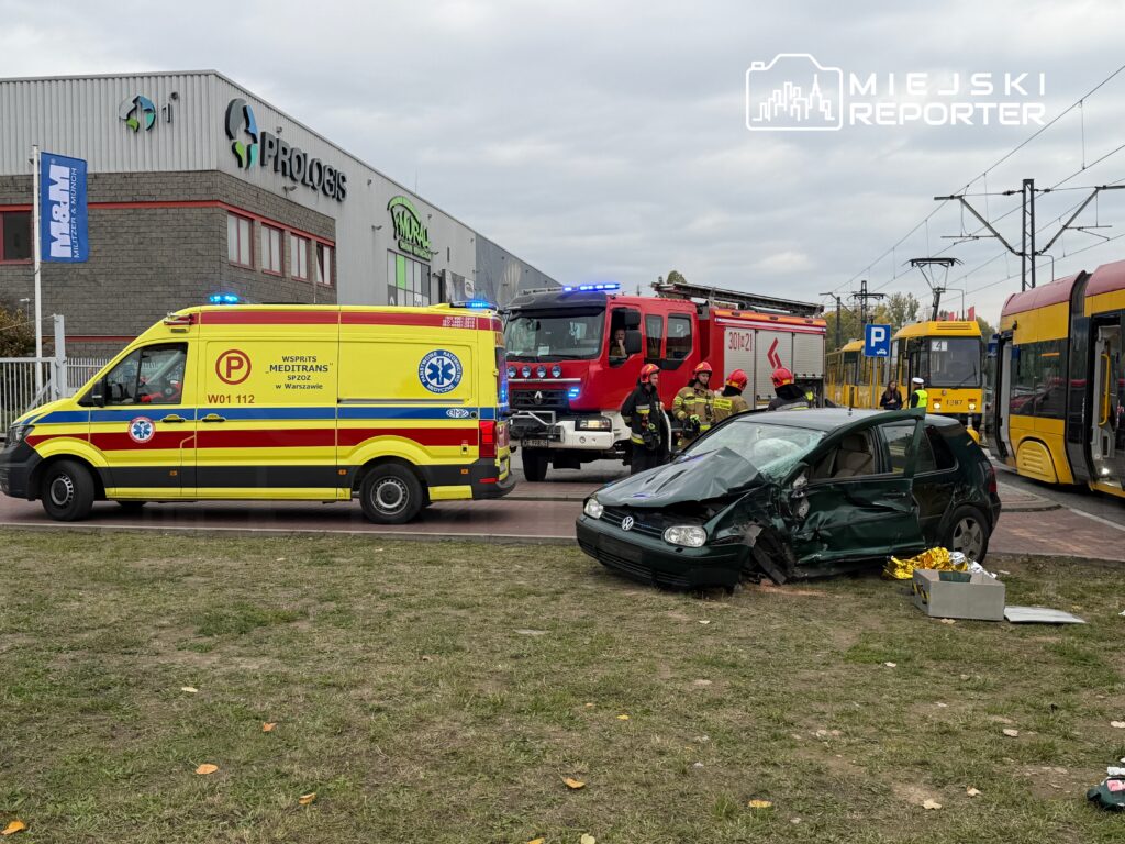 Zespół ratunkowy oraz strażacy pracują przy uszkodzonym samochodzie osobowym obok przystanku tramwajowego.