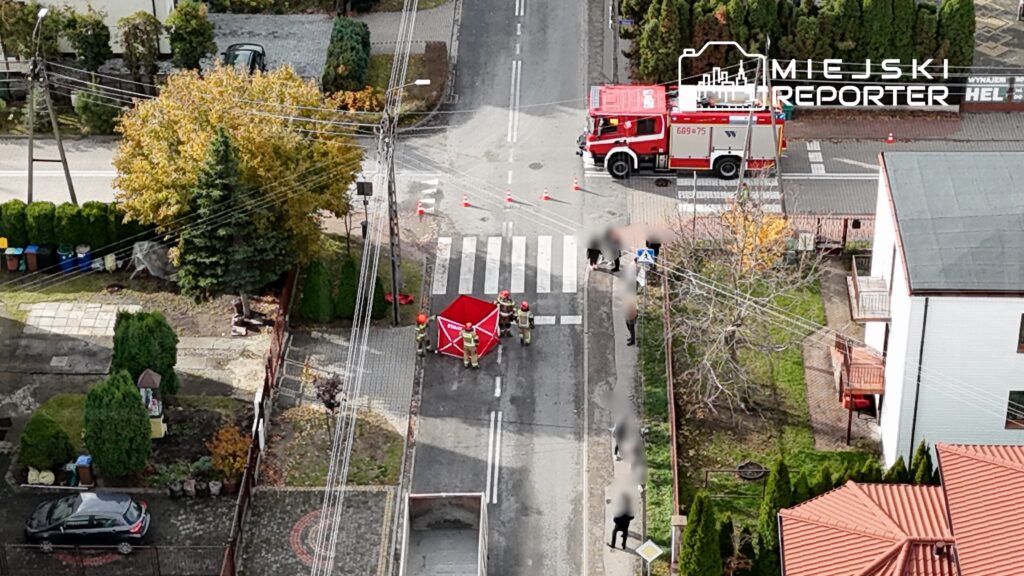 Strażacy w hełmach ustawiają czerwony namiot na przejściu dla pieszych w mieście, podczas akcji ratunkowej.