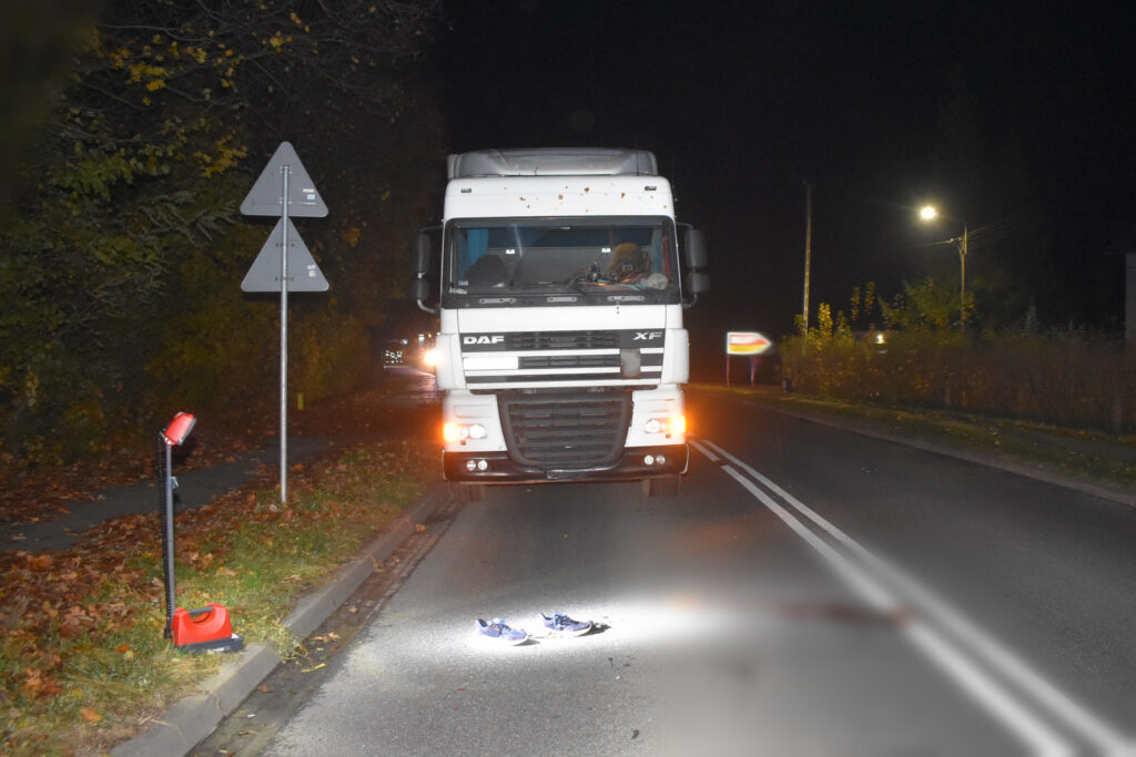 Ciężarówka DAF zatrzymana na drodze nocą, obok leżące niebieskie buty na oświetlonym asfalcie.