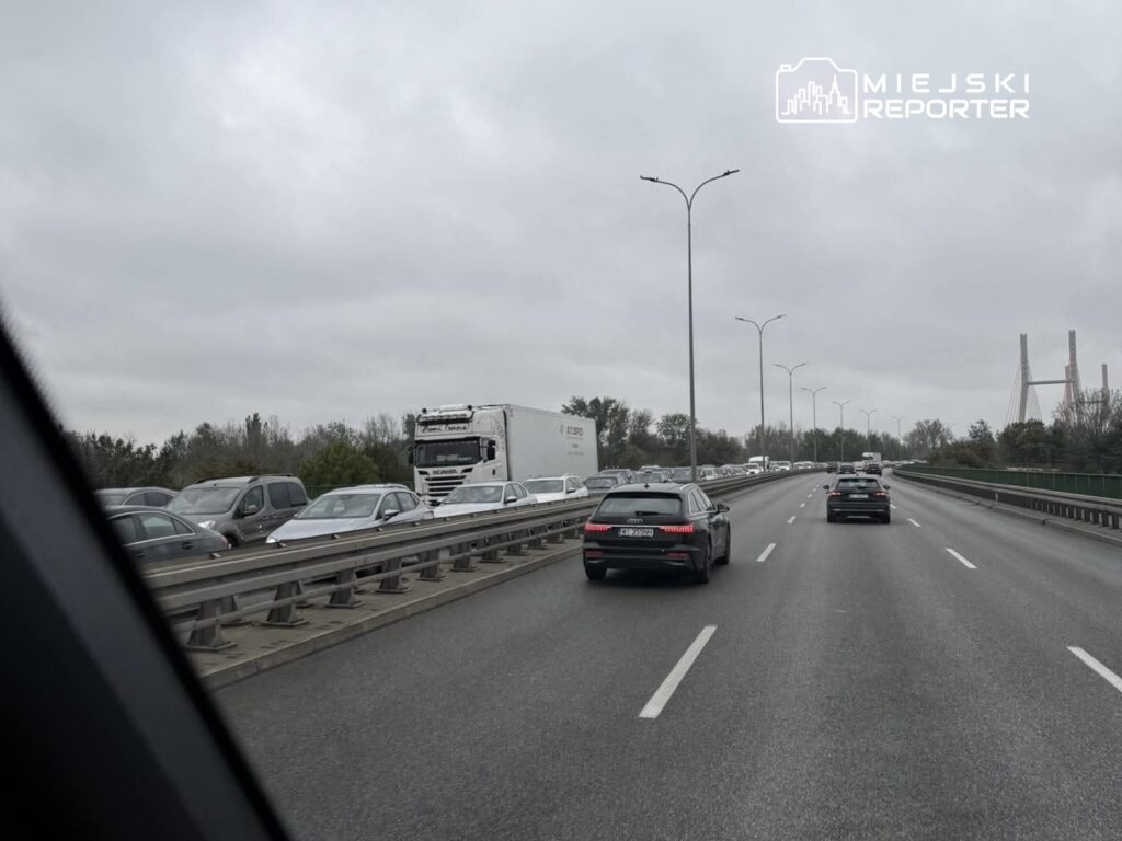 Zator drogowy na autostradzie, w tle widoczne pojazdy osobowe oraz ciężarówka, nadchmurne niebo.
