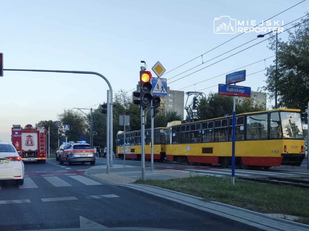 Tramwaj w żółto-czerwonym kolorze zatrzymany na torach, obok samochód straży pożarnej i radiowóz policyjny.