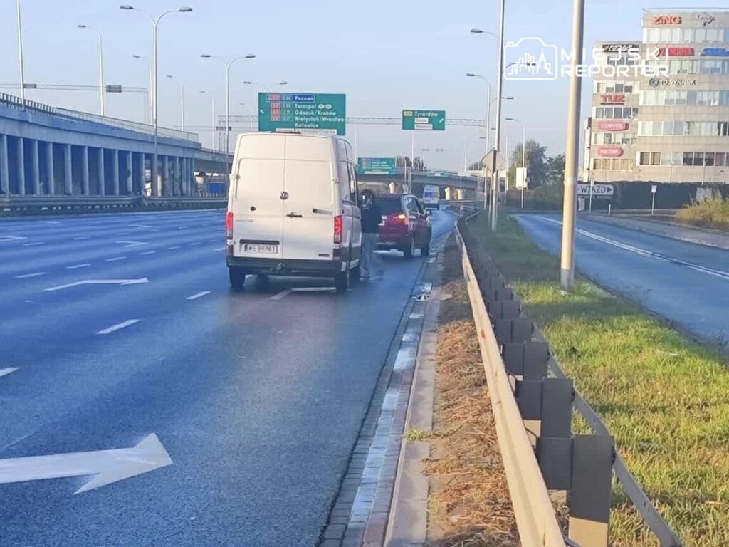 Biały furgon zatrzymany na autostradzie, obok niego stoi kierowca rozmawiający z innym kierowcą czerwonego samochodu.