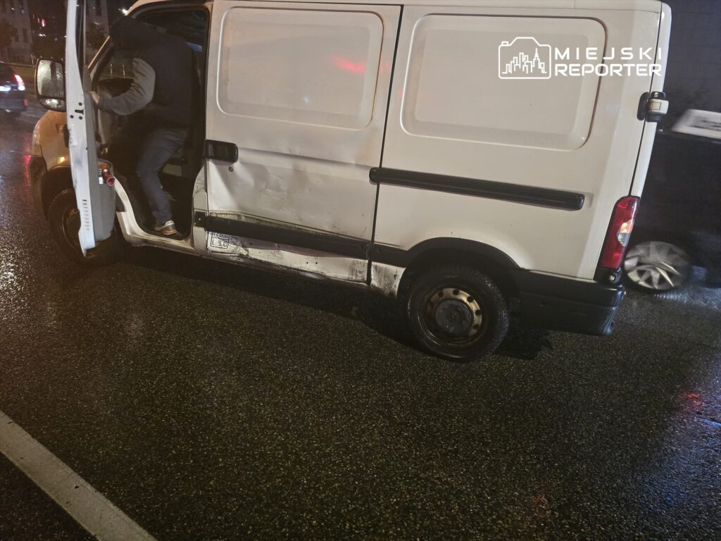 Kierowca w dżinsach wsiada do białego dostawczego vana z uszkodzeniami na drodze w deszczową noc.