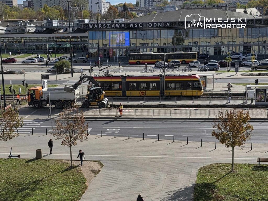 Pracownicy budowlani wykonują prace drogowe obok tramwaju w pobliżu stacji Warszawa Wschodnia.