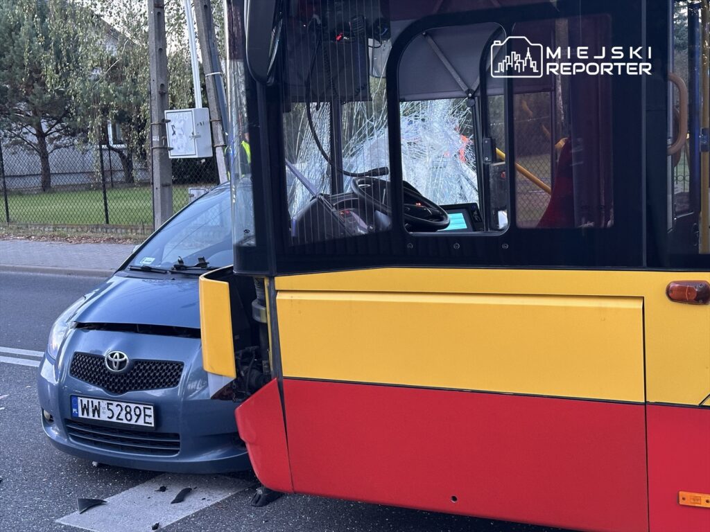 Zderzenie autobusu z samochodem osobowym na ulicy, z widocznym uszkodzeniem przodu pojazdu.