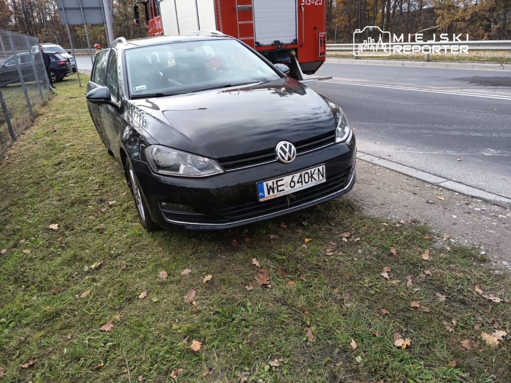 Czarny samochód osobowy marki Volkswagen zaparkowany na trawie obok ruchliwej drogi.