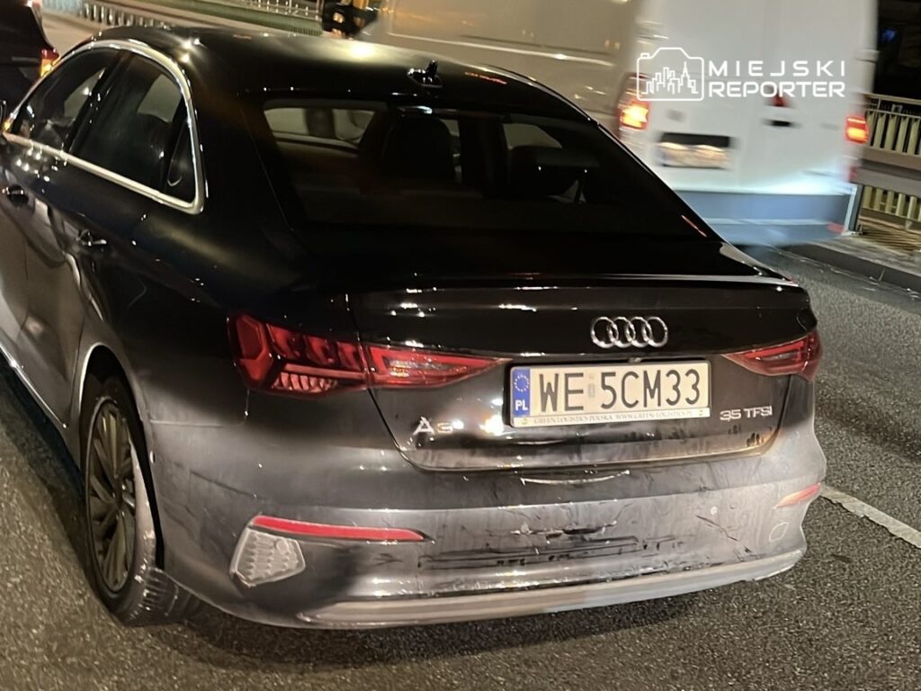 Czarny samochód marki Audi A3 stojący na ruchliwej drodze nocą, z widocznym oświetleniem tylnych lamp.