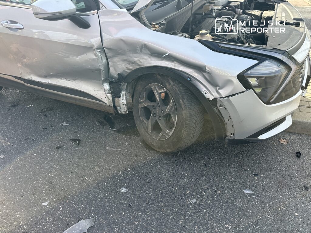 Uszkodzony samochód osobowy z wgniecioną boczną częścią stoi na ulicy, wokół leżą resztki szkła.