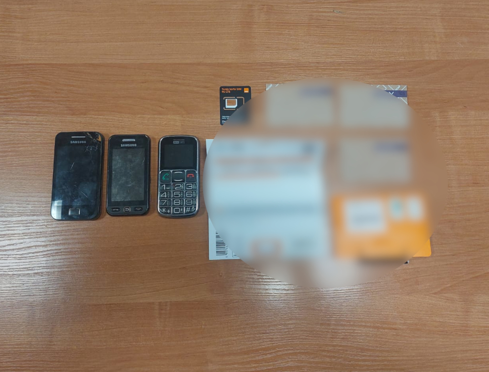 Trzy telefony komórkowe marki Samsung ułożone na drewnianym blacie, obok widoczna karta SIM.