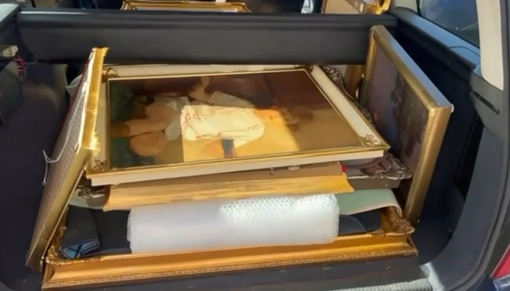 W bagażniku samochodu ułożone są obrazy w ozdobnych ramach, otoczone bąbelkową folią ochronną.