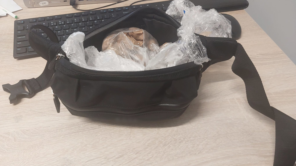 Czarna torba z otwartym zamkiem, wypełniona folią bąbelkową i zawartością, leży na biurku obok klawiatury.