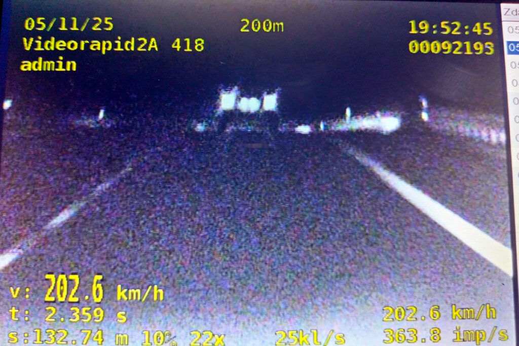 Pojazd poruszający się z prędkością 202,6 km/h na drodze, widok z kamery monitorującej.