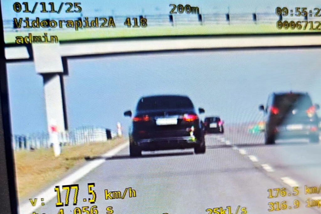 Czarny samochód osobowy porusza się z prędkością 177,5 km/h na drodze w kierunku niebieskiego nieba.