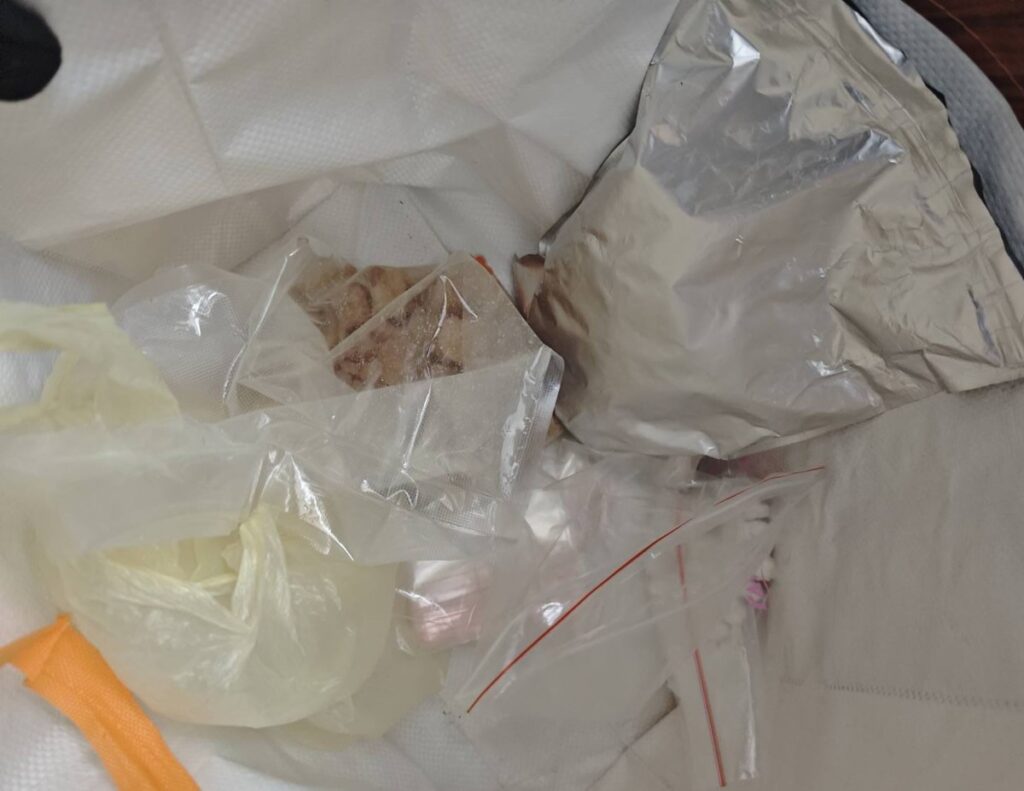 Worek z różnymi opakowaniami, w tym przezroczystymi torebkami i folią aluminiową, zawierający nieokreślone przedmioty.