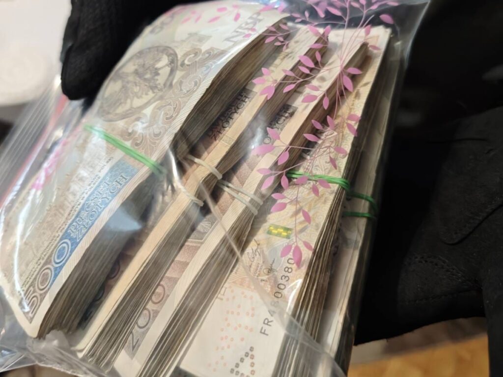 Pakiet banknotów polskich w przezroczystej torbie, trzymany w rękawiczkach, z widocznymi nominałami 200 i 500 zł.