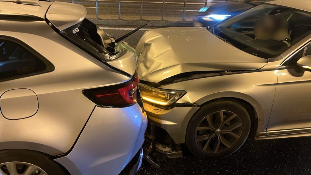 Dwa uszkodzone samochody osobowe zderzone w nocy na jezdni, jeden z pojazdów ma wgnieciony przód.