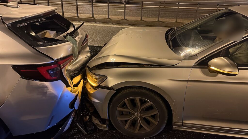 Dwa uszkodzone samochody osobowe zderzone na drodze, jeden z nich ma wgniecioną maskę, a drugi uszkodzoną tylną część.