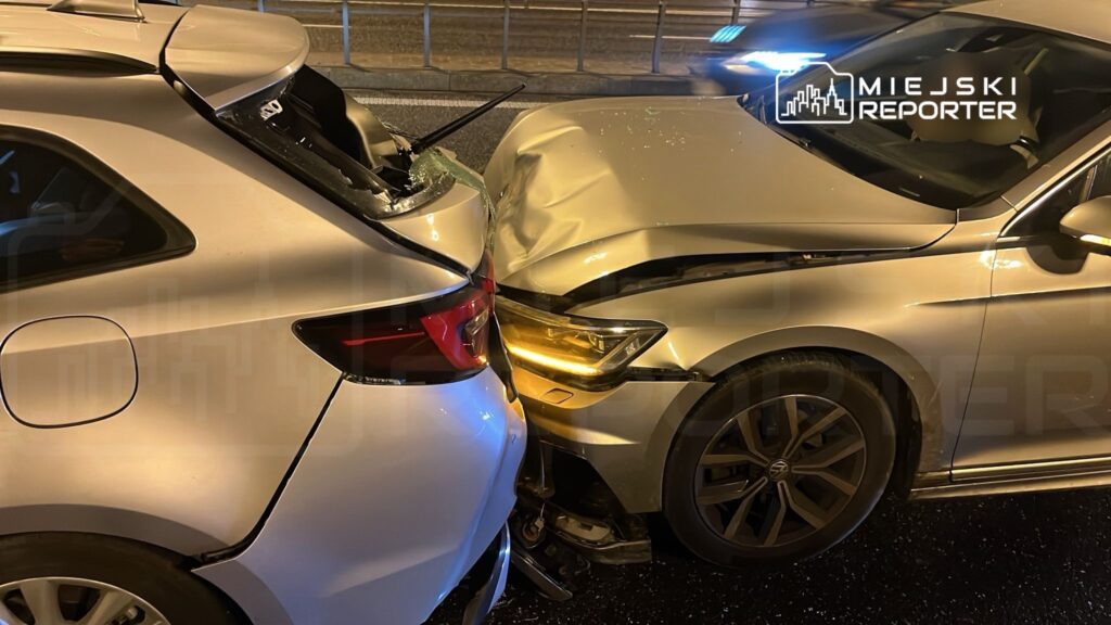 Dwa samochody osobowe zderzone na drodze, jeden z nich z wgniecionym przodem, drugi z uszkodzoną tylną częścią.