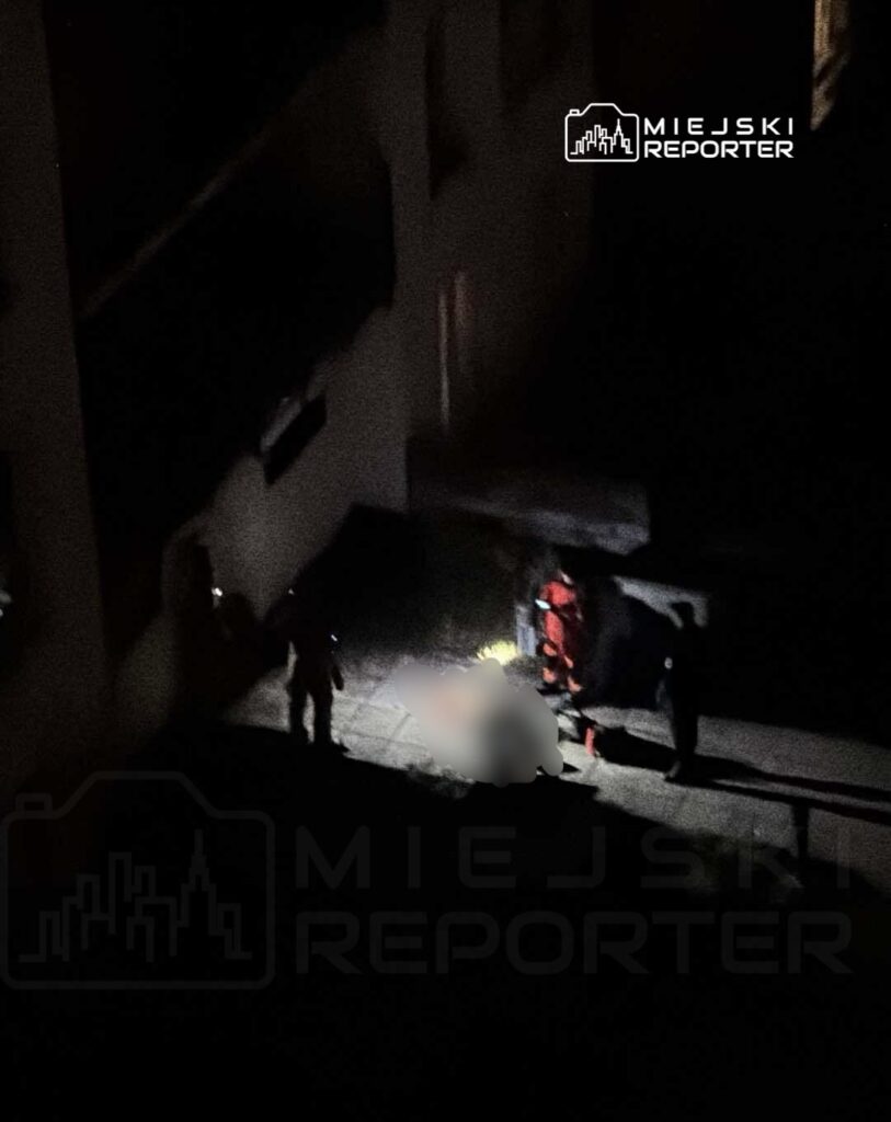 Grupa ratowników w ciemnym otoczeniu przemieszcza się w kierunku leżącej na ziemi osoby.