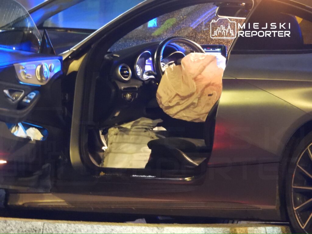 Czarny samochód osobowy z otwartymi drzwiami, w środku widoczny wystrzelony poduszka powietrzna.