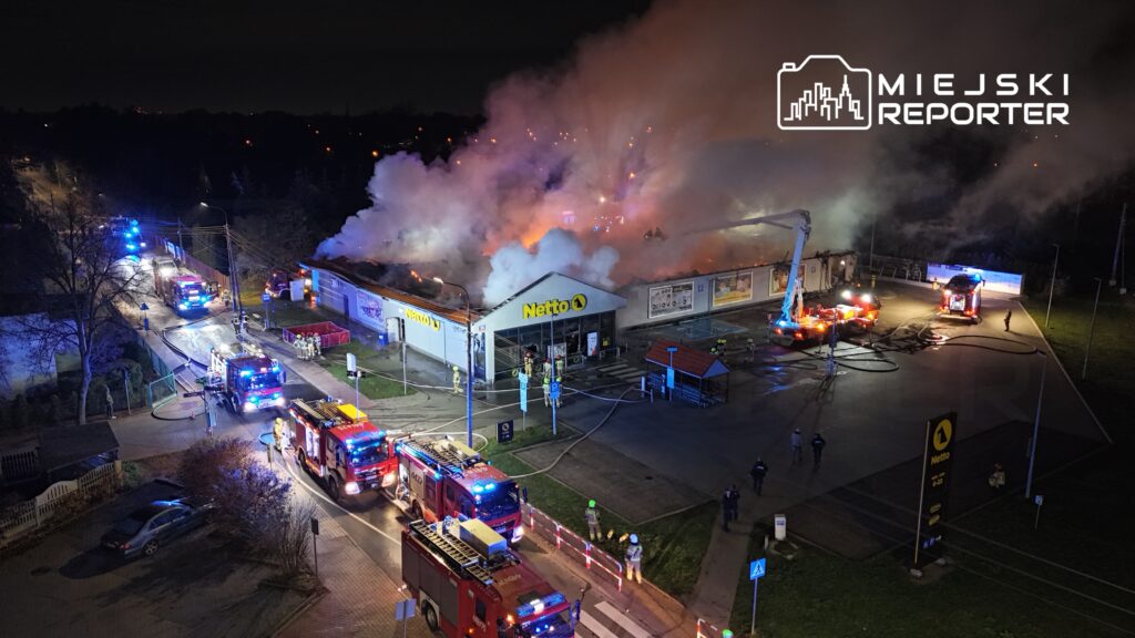Pożar w sklepie Netto, gęsty dym i ogień wydobywają się z dachu, strażacy pracują nad gaszeniem.