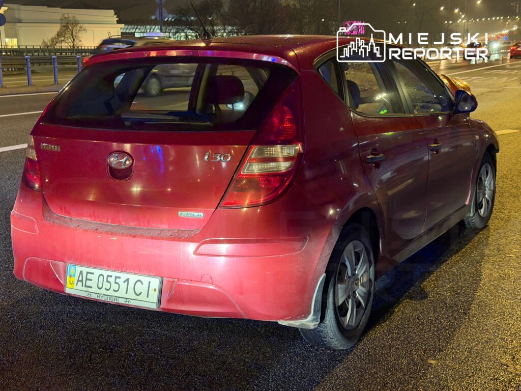 Czerwony samochód osobowy marki Hyundai i30 zaparkowany na poboczu drogi, widoczny w nocy.