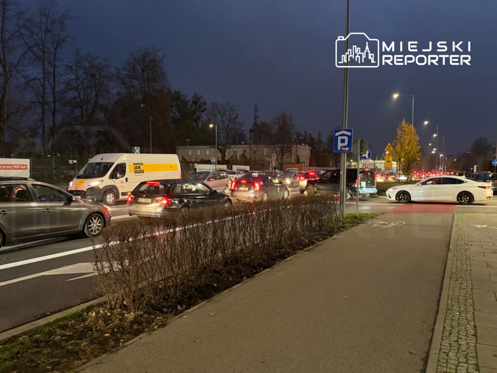 Zatłoczona ulica z samochodami w korku, a w tle widoczny biały van z reklamą.