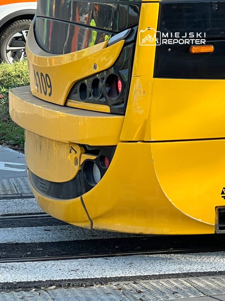 Żółty tramwaj z uszkodzoną tylną częścią stoi na torach, obok widoczne są pasy ruchu.