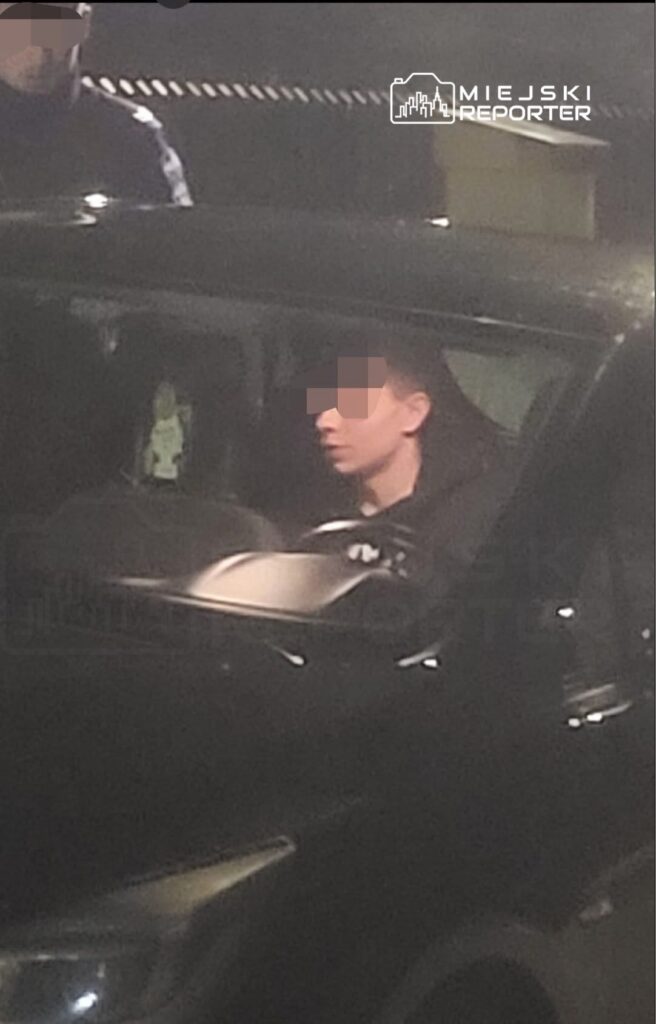 Mężczyzna siedzący w samochodzie osobowym, w ciemnym otoczeniu, z wyraźnym skupieniem na twarzy.