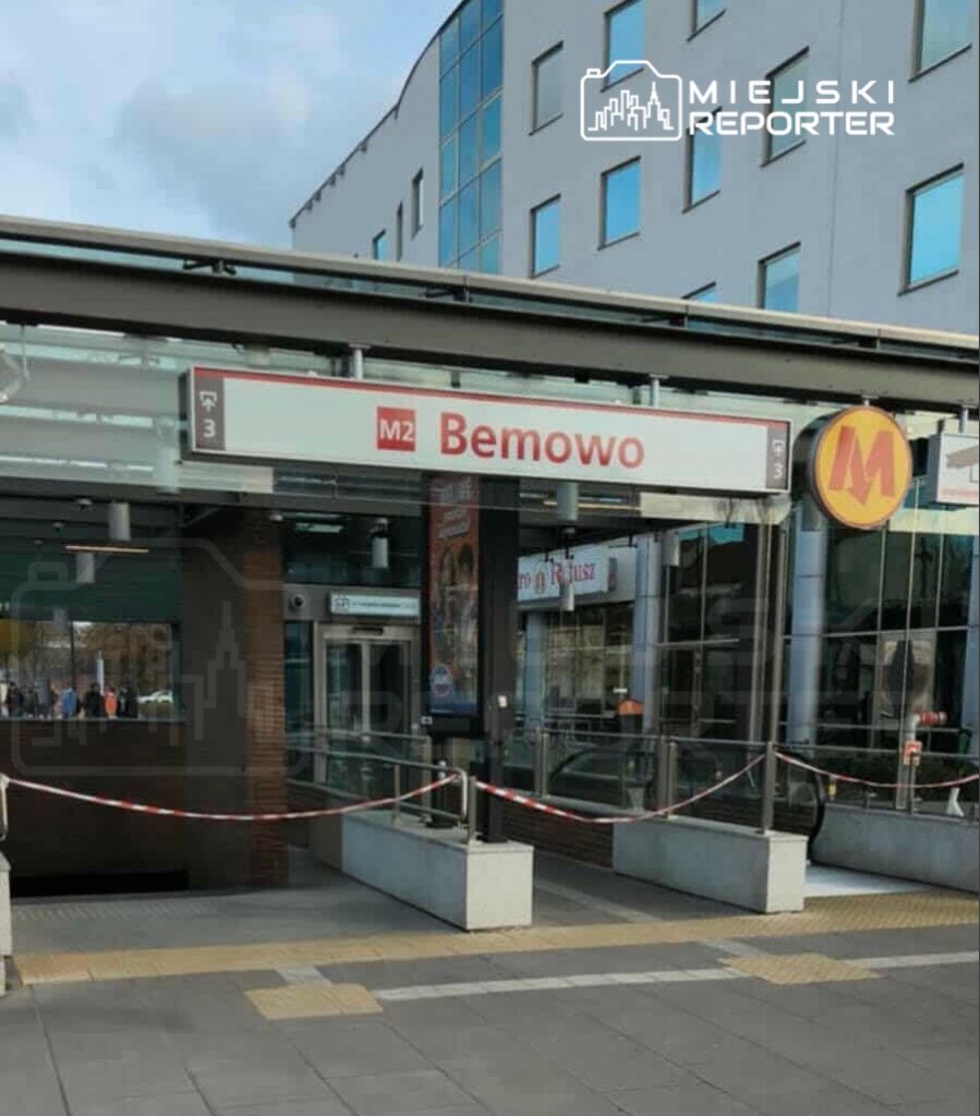 Stacja metra z oznaczeniem "Bemowo" i zamkniętym wejściem, w tle nowoczesny budynek biurowy.