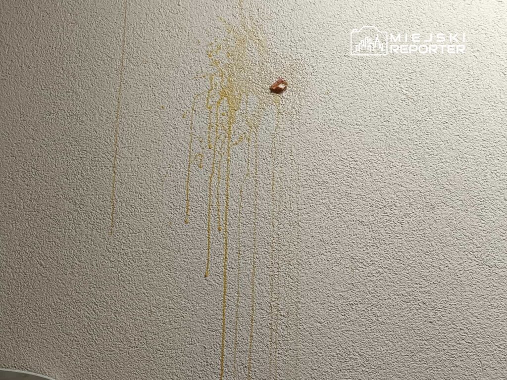 Na ścianie widać żółte smugi, które spływają w dół, obok znajduje się mały kawałek materiału.