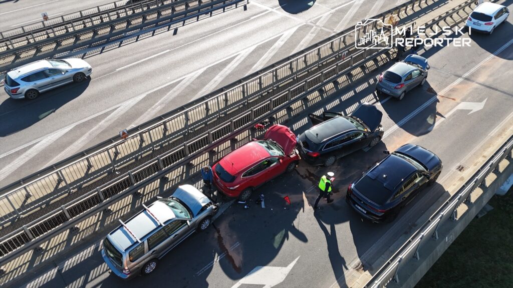 Na drodze doszło do kolizji trzech samochodów, a policjant zabezpiecza miejsce zdarzenia.