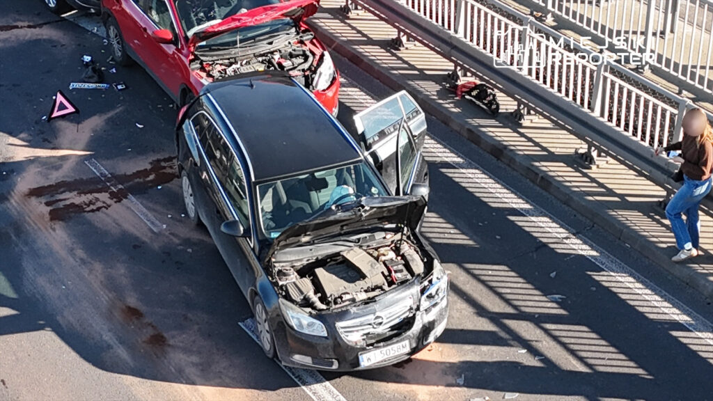 Dwa uszkodzone samochody stoją na drodze, z otwartymi maskami, obok leży trójkąt ostrzegawczy.