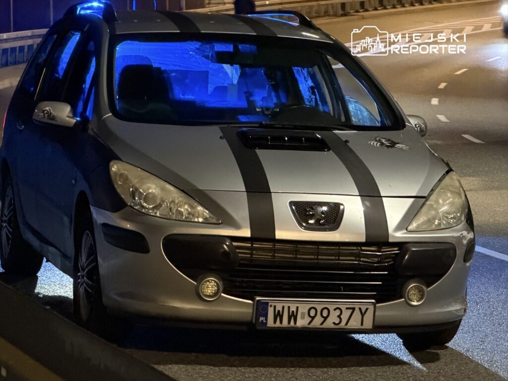 Samochód osobowy marki Peugeot z niebieskimi światłami, zaparkowany na drodze w nocy.