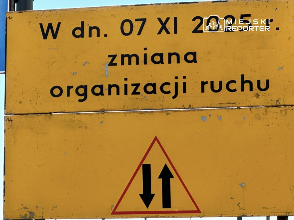 Zółta tablica informacyjna z datą "07 XI 2005" i napisem "zmiana organizacji ruchu", z symbolem strzałek.