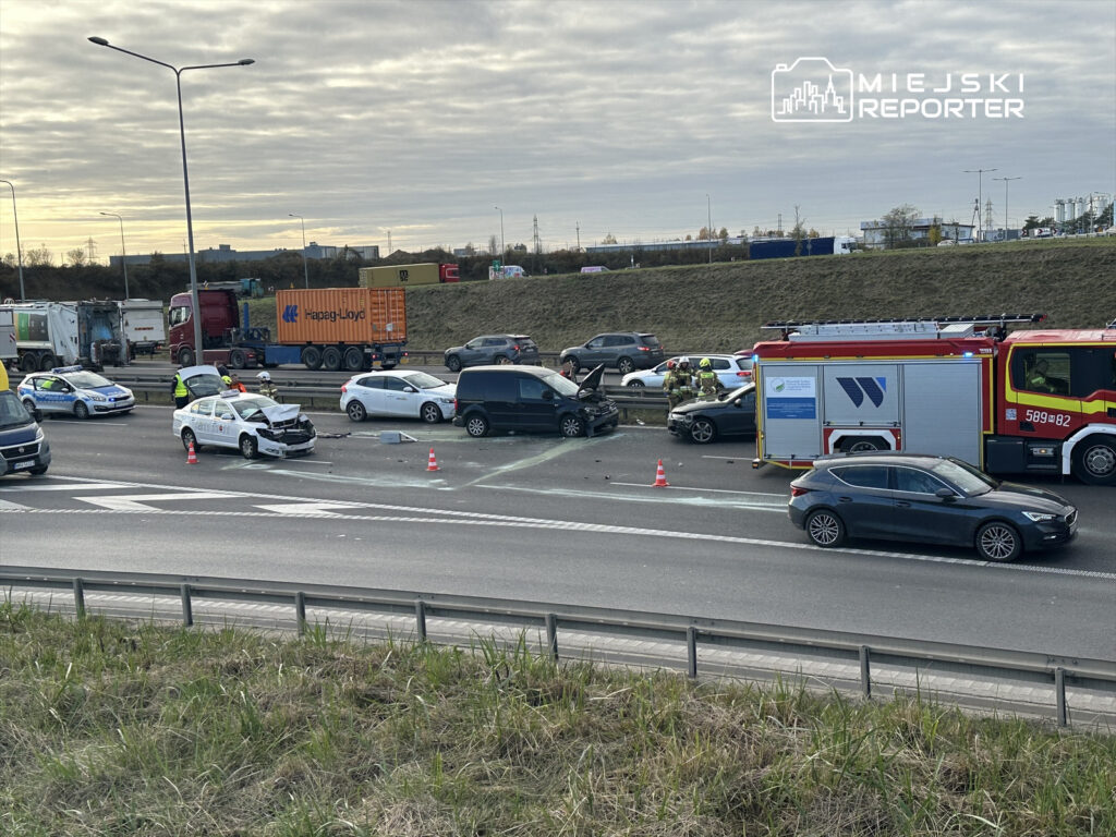 Wielokrotny wypadek drogowy na autostradzie, z uszkodzonymi pojazdami i obecnością służb ratunkowych.