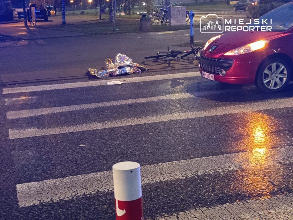 Czerwony samochód zaparkowany na przejściu dla pieszych obok leżącego na ziemi foliowego pakunku.