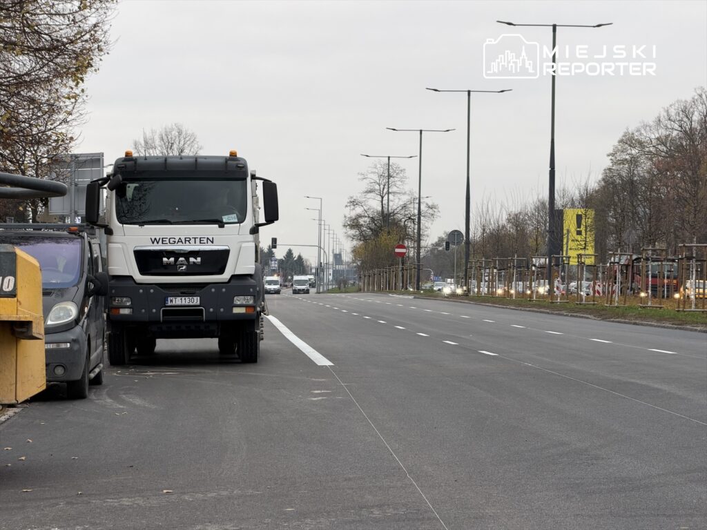 Ciężarówka marki MAN z napisem "WEGARTEN" stoi na nowo wyremontowanej drodze obok małego pojazdu.