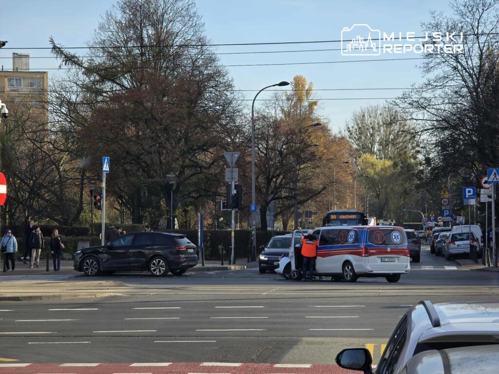 Kierowca z kamizelką odblaskową rozmawia z pasażerem w samochodzie dostawczym na skrzyżowaniu ulicy.